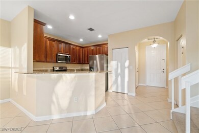 Kitchen featuring arched walkways, light stone countertops, light tile patterned flooring, stainless steel appliances, and recessed lighting