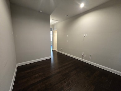 Empty room featuring dark wood finished floors and baseboards