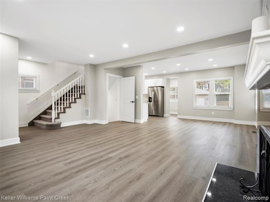 Unfurnished living room featuring stairway, light wood-type flooring, and recessed lighting