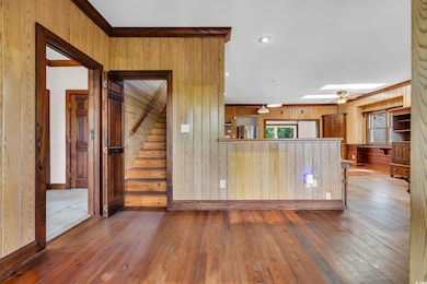 Kitchen with a skylight, stainless steel fridge with ice dispenser, hardwood / wood-style flooring, wood walls, and healthy amount of natural light