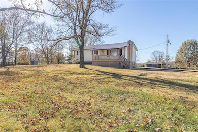 Single story home with a metal roof, a front lawn, and a deck