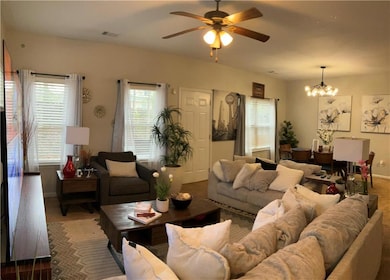 Carpeted living area featuring ceiling fan and a chandelier