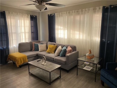 Living room featuring a wealth of natural light, crown molding, hardwood / wood-style floors, and ceiling fan