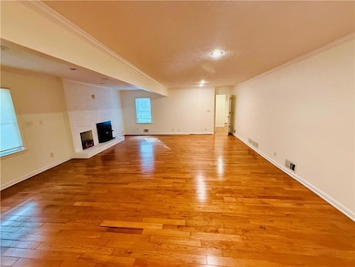 Unfurnished living room with ornamental molding, light wood-style flooring, and a fireplace