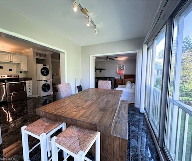 Dining room featuring stacked washer / dryer, ceiling fan, track lighting, and dark marble finish floors