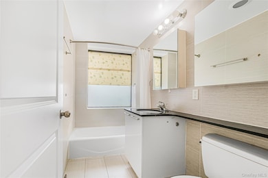 Bathroom featuring vanity, shower / bath combo with shower curtain, and light tile patterned flooring