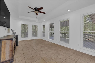 Unfurnished sunroom with a tray ceiling and ceiling fan