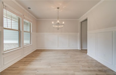 Unfurnished room with a chandelier, crown molding, and light hardwood / wood-style floors