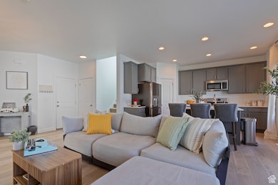 Living room featuring light wood-style flooring, recessed lighting, and stairway