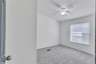 Unfurnished room featuring visible vents, a textur