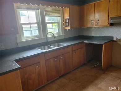 Kitchen with brown cabinetry, plenty of natural light, and tasteful backsplash
