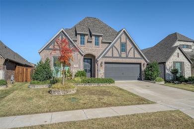 View of front facade with brick siding, roof with shingles, a front lawn, driveway, and a garage