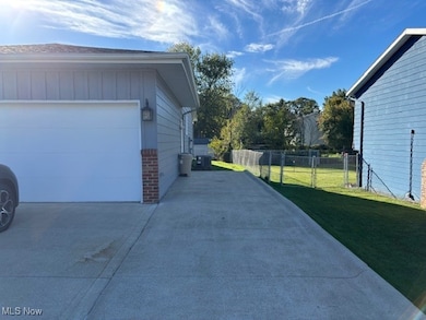 View of side of home featuring board and batten siding, driveway, and a garage