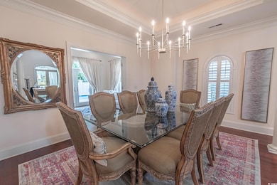 Dining room featuring a chandelier, crown molding, baseboards, and wood finished floors