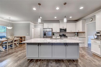Kitchen featuring ornamental molding, an island with sink, stainless steel appliances, and a sink