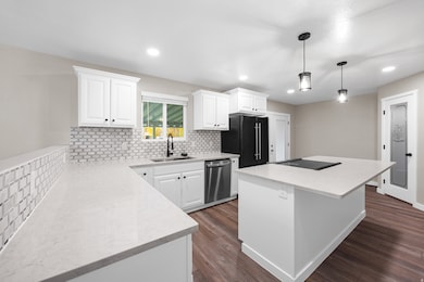 Kitchen featuring tasteful backsplash, white cabinetry, a center island, dark wood-type flooring, and recessed lighting