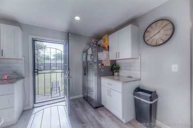 Doorway with light wood-style floors, baseboards,