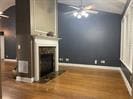 Unfurnished living room featuring a ceiling fan, a fireplace, wood finished floors, and baseboards