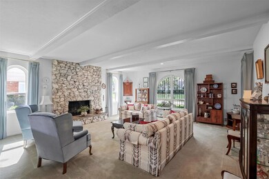 Carpeted living room with a fireplace and beam cei