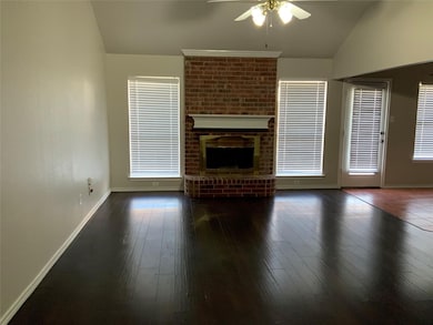 Unfurnished living room featuring lofted ceiling, ceiling fan, dark wood finished floors, and a brick fireplace