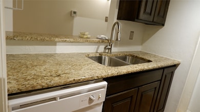 Kitchen featuring dark brown cabinetry, granite countertops, and white appliances