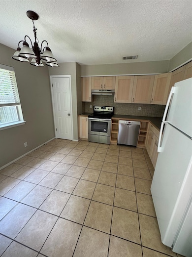 Kitchen featuring light brown cabinetry, electric