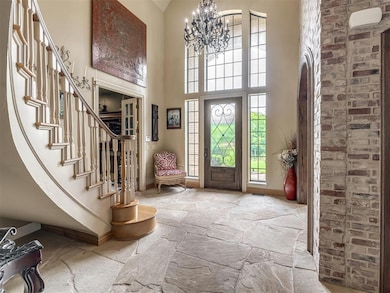 Entryway with stone floors, a high ceiling, a chandelier, and stairway
