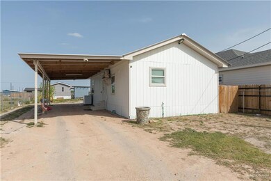 View of property exterior with an attached carport, fence, and dirt driveway