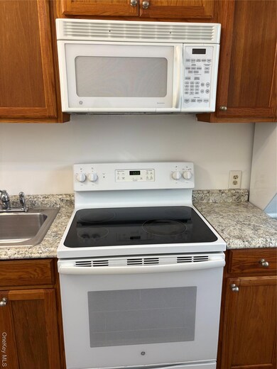 Kitchen featuring white range with electric cooktop and brown cabinets