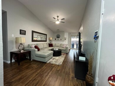 Living room with ceiling fan, lofted ceiling, and dark wood-type flooring