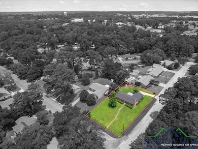 Aerial view of residential area featuring property parcel outlined and a heavily wooded area