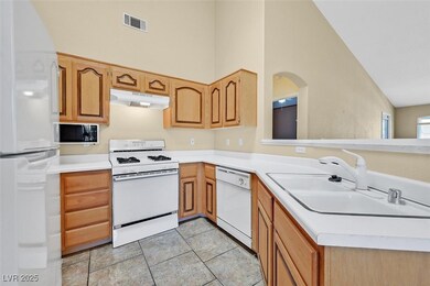 Kitchen with white appliances, under cabinet range hood, light countertops, high vaulted ceiling, and light tile patterned floors