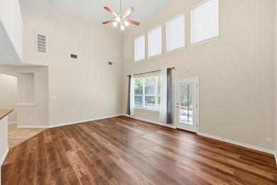 Unfurnished living room with light wood finished floors, ceiling fan, a high ceiling, and arched walkways