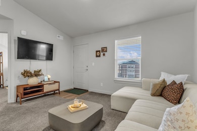 Carpeted living room featuring vaulted ceiling and baseboards