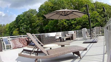 View of the party deck with plush sofa and chairs as well as a large umbrella and cushioned lounge chairs. dining table, and large coffee table. Also a storage box. Aprrox 500 sq. ft. The railing, stairs and floor are aluminum.