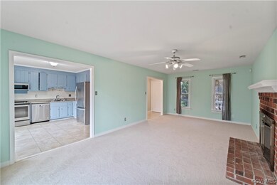 Unfurnished living room with a brick fireplace, ceiling fan, light colored carpet, and sink