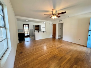 Unfurnished living room featuring ceiling fan, ha