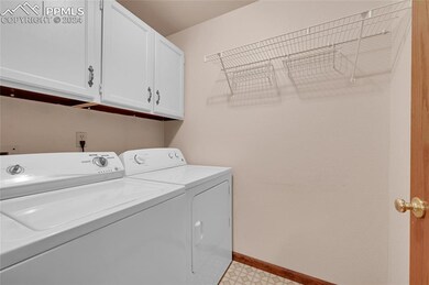 Clothes washing area featuring cabinets, washer an