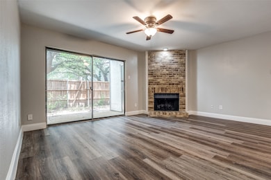 The cozy living area with wood burning fireplace features a sliding glass door to back patio and yard, ceiling fan and is adjacent  to the kitchen.