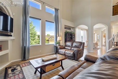Living area featuring arched walkways, a towering ceiling, and tile patterned flooring