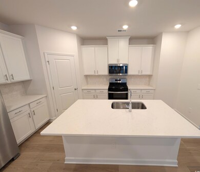 Kitchen with decorative backsplash, light stone counters, white cabinetry, and recessed lighting