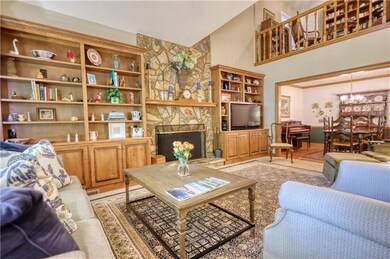 Living area featuring high vaulted ceiling, a stone fireplace, and a chandelier
