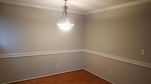 Spare room with ornamental molding and wood finished floors