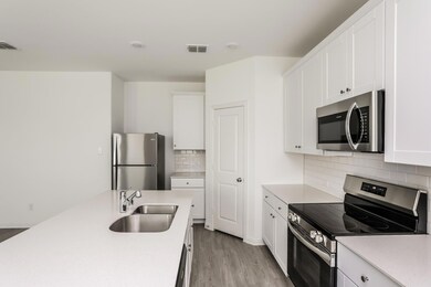 Kitchen with light hardwood / wood-style floors, sink, stainless steel appliances, and white cabinets