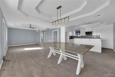 Main House Dining room area with light hardwood / wood-style flooring, ceiling fan, and a tray ceiling