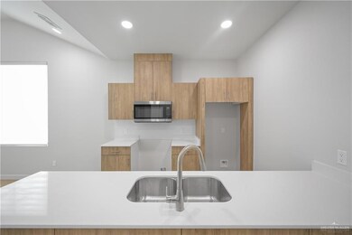 Kitchen with light countertops, stainless steel microwave, a sink, and recessed lighting