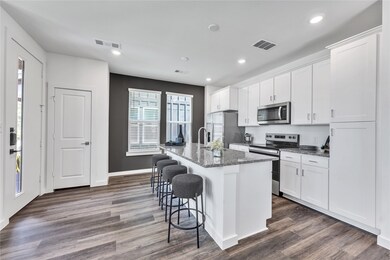 Kitchen with appliances with stainless steel finishes, an island with sink, a breakfast bar, and visible vents