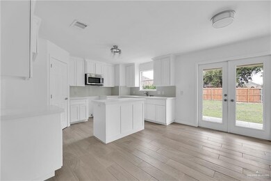Kitchen featuring tasteful backsplash, french doors, a center island, light hardwood / wood-style floors, and white cabinetry