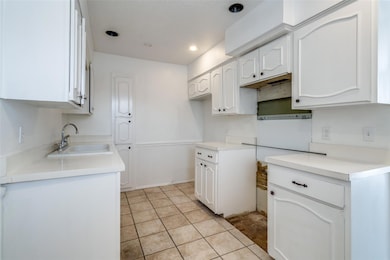 Kitchen featuring white cabinetry, a sink, recesse