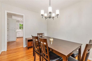 Dining room featuring light wood-style floors, a chandelier, and baseboards